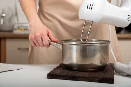 Cook prepares a dough. Mixer mixes the ingredients in saucepan