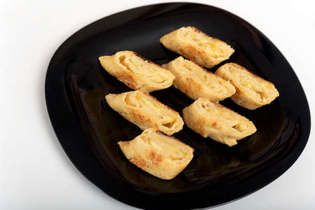 Pieces of apple roll on the black plate. Apple strudel. Home baking.
