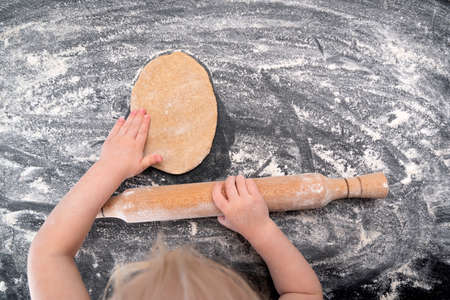 Top view Child rolling dough for shortbread cookies at home kitchen