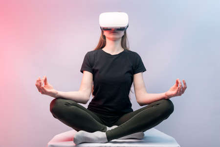 Girl experiencing virtual reality. Woman in VR glasses meditatesの写真素材