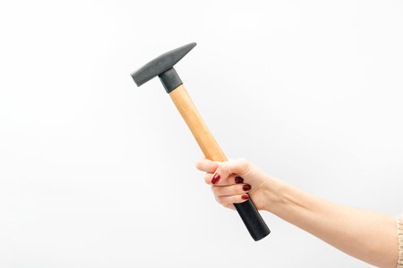 Female hand with red manicure holds hammer isolated on white backgroundの写真素材