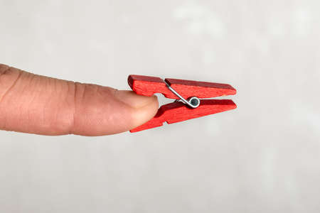 Wooden clothespin that is stuck on an index finger. Trouble concept.の写真素材