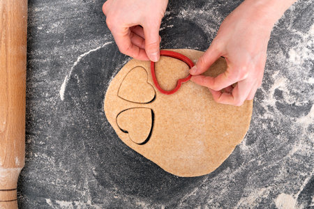 Cropped image of girl making heart shaped dough. Process of making shortbread cookies.