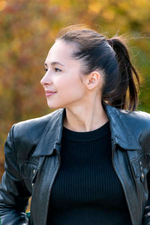 Portrait of brunette girl outdoors. Young woman in black. Happy beautiful young woman. Vertical frame.の写真素材