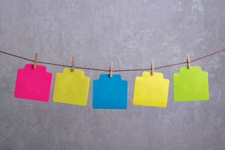 Blank multicolored paper cards hang with clothespin on rope. Copy space. Place for your text