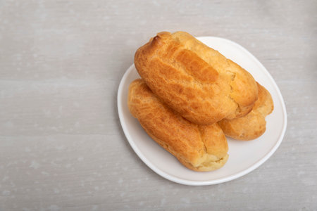 Air eclairs on white saucer. Close up, top view. Profiteroles, puffs or popovers