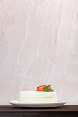 Cheesecake with strawberries on white plate on light background. Vertical frame.