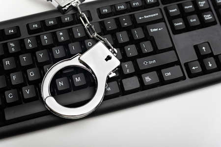 Handcuff is on the keyboard. Online fraud and criminal liability. Internet scam concept.の写真素材