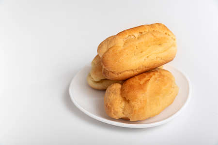 Profiteroles or eclairs without cream on white saucer. White background. Homemade baking.の写真素材