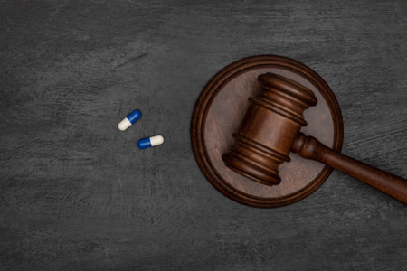 Judge gavel and two pills. Illegal use of drugs. Pharmaceutical lawsuit. Black background.の写真素材