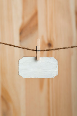 Blank wooden sign hang with clothespins on rope on wooden background. Small nameplate. Copy space. Vertical frameの写真素材