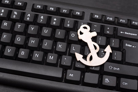 Black computer keyboard and anchor. Close up.の写真素材