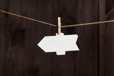 Blank arrow pointer hang with clothespins on rope, wooden background. Small nameplate. Copy spaceの写真素材