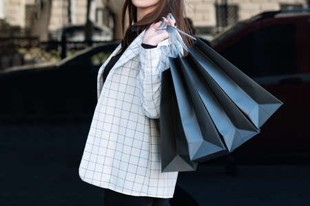 Girl in jacket holds several shopping bags on black background. Black Friday, sale, discount.の写真素材