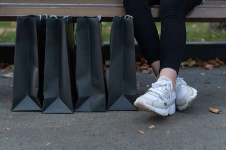 Womens feet in sneakers and paper shopping bags. Black Friday discounts.