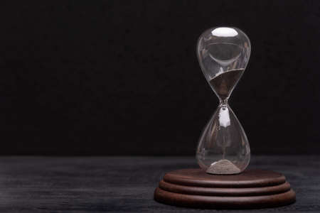 Hourglass on black background. Urgency and outcome of time. Time managementの写真素材