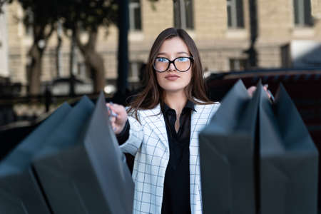 Stylish young woman in glasses with black bags after successful shopping. Girl shopaholic. Black Friday, sale, discount.の写真素材