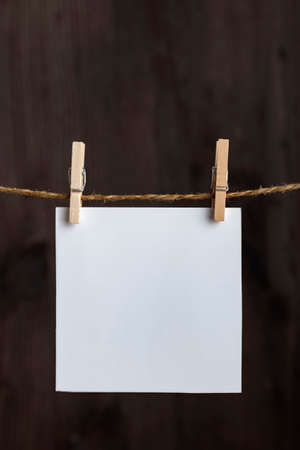 White blank notes hanging with clothespins on rope on wooden background. Copy space. Space for your text. Vertical frame.の写真素材