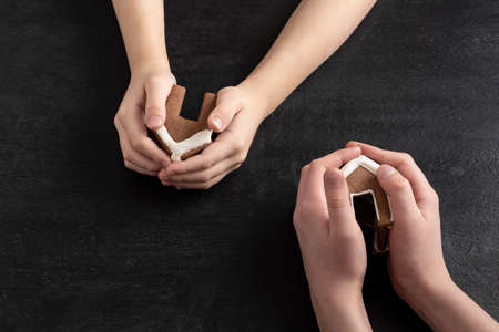 Gingerbread houses in childrens hands. Top view on black background.の写真素材