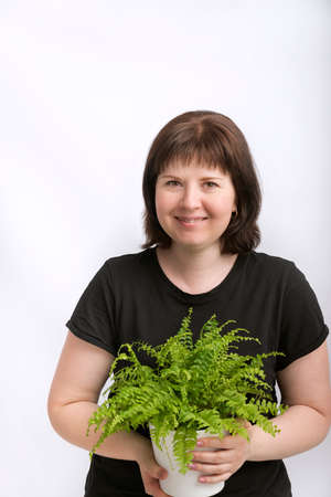 Portrait of young woman with kind eyes with house plant in hands isolation on white background. Happy woman.の写真素材
