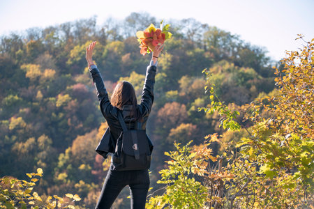 Girl holds bouquet of leaves and enjoys warm spring day. Beautiful girl on autumn park background....