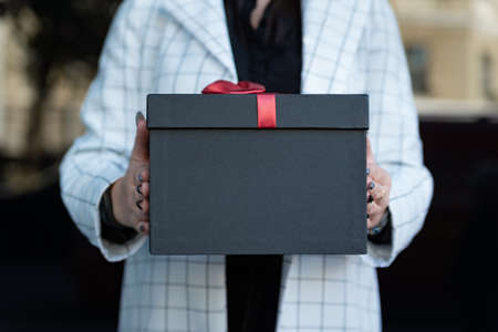 Close up photo of black gift box in female hands. Girl holding a beautiful gift box in her hands. Copy space.の写真素材