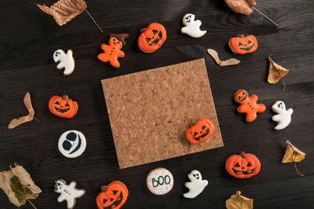 Halloween orange and white gingerbread cookies lie on a dark wooden table. Halloween concept with homemade cookies. Copy spaceの写真素材