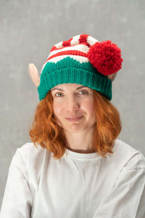 Portrait of a beautiful red-haired young girl in knitted elf hat. Vertical frameの写真素材