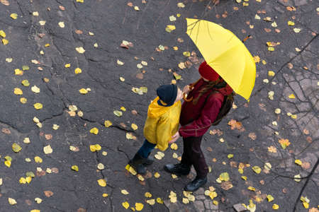 Mom and child standing down the street in the rain. Top view.の写真素材