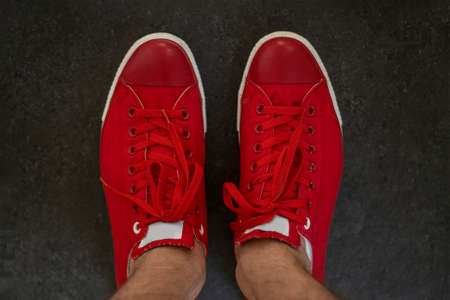 Red mens sneakers top view. Fashionable mens shoes of bright red color on grey backgroundの写真素材