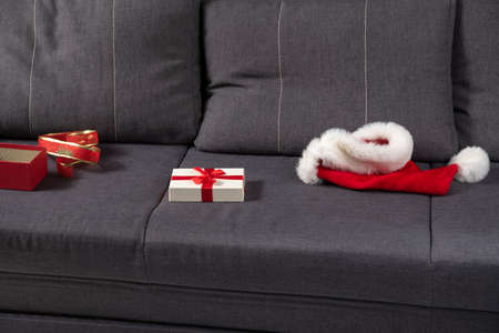 Santa hat and open gift box on couch. End of New Years Eve.の写真素材