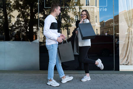 Young woman and her boyfriend with black shopping bags. Happy couple after successful shopping.
