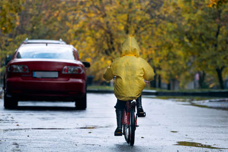 Child rides bicycle alone on the road. Child safety on the road. Back view.の写真素材
