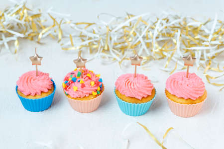 Muffins with pink buttercream frosting with candle in the shape of star. Delicious party food