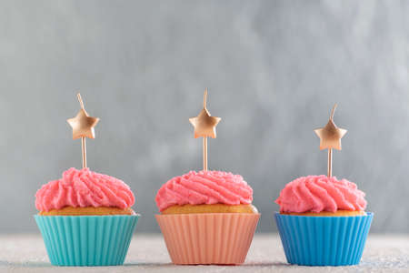 Tasty cupcakes with pink cream icing and candles. Sweet delicious muffins with copy space. Silver background.の写真素材