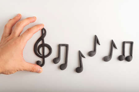 Mans hand holds violin key and notes on white background. Treble clef. Key of Gの写真素材
