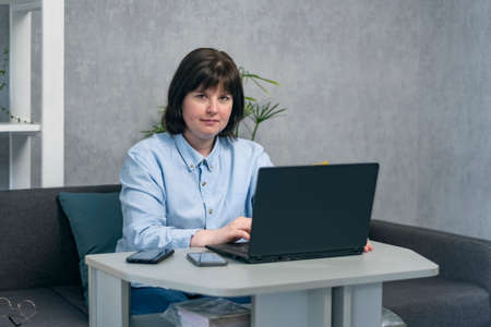 Portrait of woman while working at laptop at home. Business woman, entrepreneur, freelancer