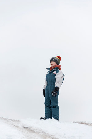 Boy plays outside during snowfall. Winter holidays. Child walks outdoors in winterの写真素材