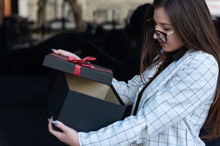 Business woman opens gift. Brunette girl holding gift box. Girl holding a beautiful gift box in her...