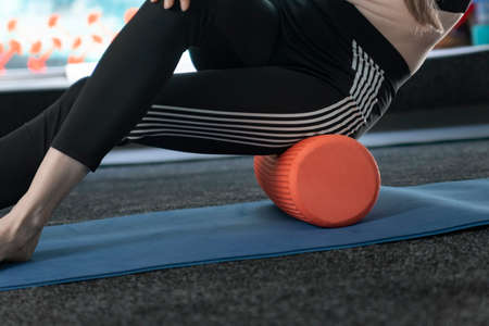 Girl kneads the thigh muscles with an MFR roller. Myofascial release. Self-massage. Fascia releaseの写真素材