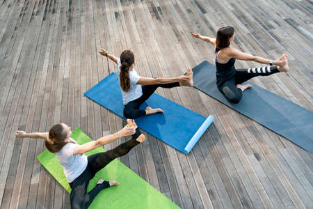 Three girls do yoga on outside. Morning yoga practice. Outdoor fitness. Healthy lifestyleの写真素材