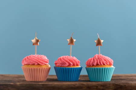 Three festive muffins decorated with candles in the form of stars on blue background. Greeting card. Copy spaceの写真素材