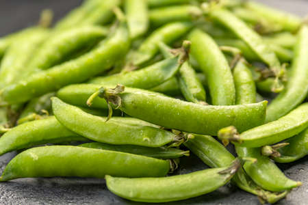 Close up photo green pods of fresh just ripped off peas. Vegetable background. Legumes