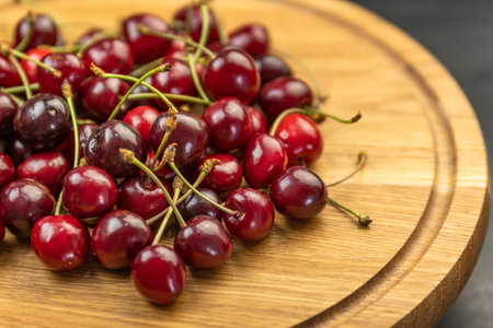 Close up ripe juicy red cherries on wooden plate. Organic farm cherries. Seasonal berriesの写真素材