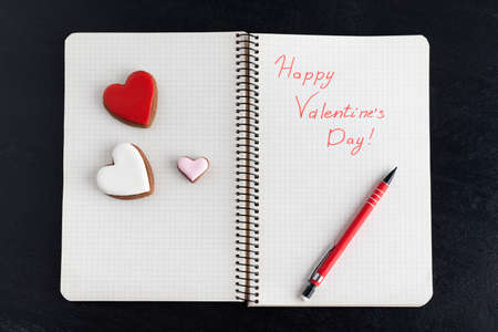 Handwritten notebook with Happy Valentines Day and three heart-shaped cookies.