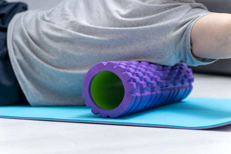 Man doing fascia exercise. Foam roller back pain treatment and myofascial release. Tools for self-massage. Workout at homeの写真素材