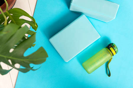 Top view of bluey yoga mat, bottle with water and yoga bricks. Stretching tools. Fitness Equipmentの写真素材
