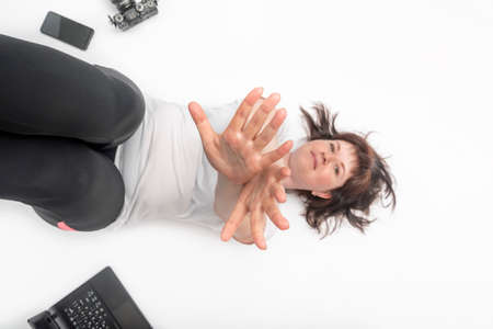 Top view portrait of young woman on white background surrounded by gadgets - laptop, phone and...