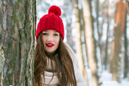 Young brunette caucasian woman standing in a sunny coniferous snowy winter forest. Outdoors. Copy...
