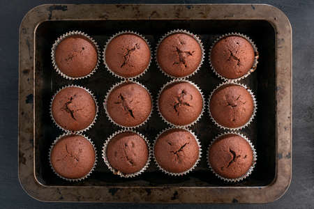 Just baked chocolate cupcakes on baking sheet. Homemade muffins for dessert. Top view. Close upの写真素材